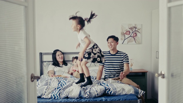 年轻的中国女孩在母亲节快乐地在床上跳(慢镜头)视频素材