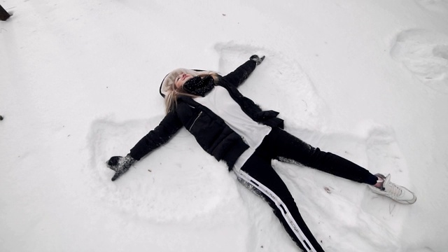 雪天使俯视图。快乐的女人躺在雪里，做雪天使视频素材