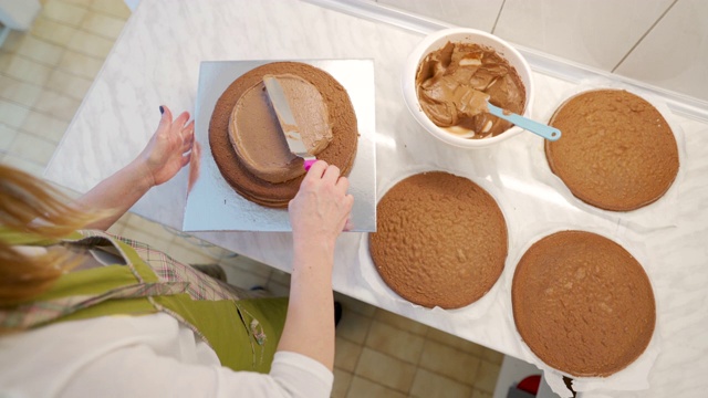 一个女人正在搅拌并在蛋糕上涂奶油视频下载