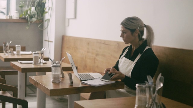 拉丁美洲的咖啡馆经理使用笔记本电脑工作视频下载