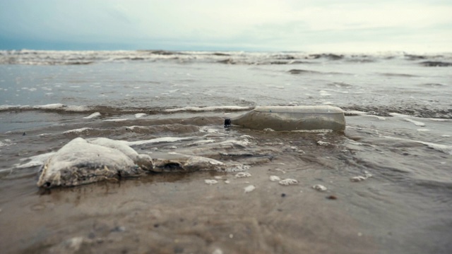 以海洋为背景的塑料垃圾和海滩上的垃圾的慢镜头，概念拯救世界和海滩污染视频素材