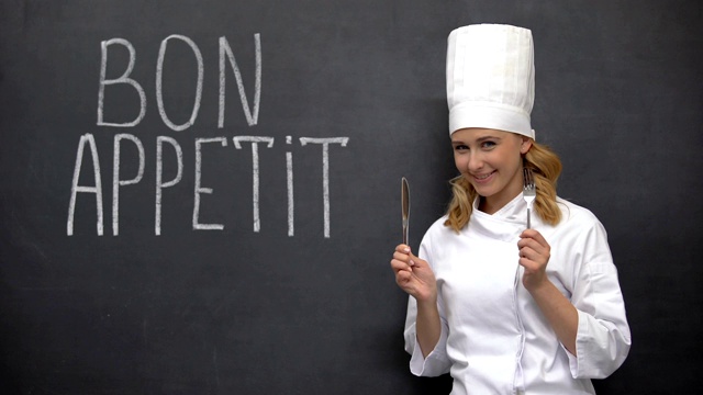 厨师拿着刀叉，在“好胃口”法语短语“美食”旁边摆姿势视频下载