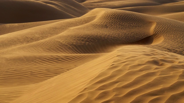 日落在沙漠。沙漠里的沙丘里，沙子随风摇摆。沙丘上布满了褶皱。UHD视频素材