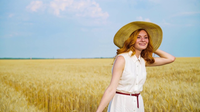 夏天，穿着白衣、戴着草帽的年轻女子走在麦田里视频下载