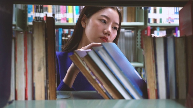一个亚洲女人在图书馆找书的4k视频场景视频素材