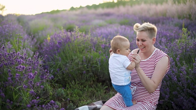 快乐的妈妈带着小儿子在薰衣草地里玩耍视频下载