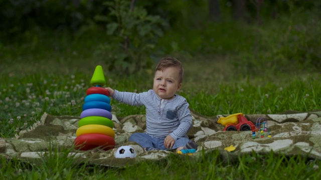 美丽的小男孩独自在花园里玩。视频下载