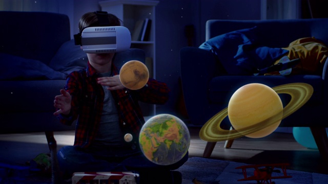 晚上睡觉前:小男孩戴着增强现实耳机玩空间学习软件，用手势操纵3D行星，发现太阳系和宇宙的事实视频下载