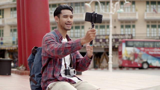 英俊的年轻亚洲男子的肖像独自游客在泰国的巨大秋千拍照。亚洲男子博客在手机上录制视频，快乐地享受休闲生活方式旅行。视频素材