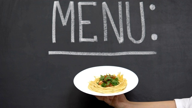 手展示盘子美味的意大利面，菜单写在黑板上，餐厅视频下载