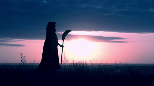 侧影女巫与扫把站在山上傍晚天际线万圣节视频素材