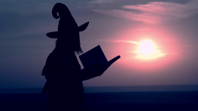 一个穿着女巫服装读魔法书的女人视频素材