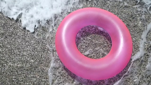 在康沃尔纽基的海岸线上，粉红色的橡胶圈被海浪抓住，5 X慢镜头。视频下载