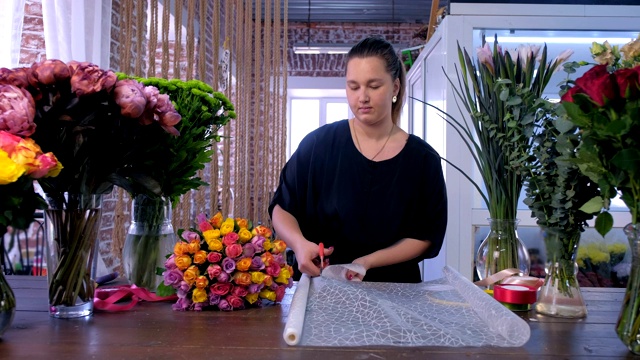 女花店工在花店切纸包装花束。视频下载