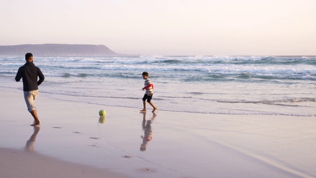 爸爸和儿子在沙滩上踢足球视频素材