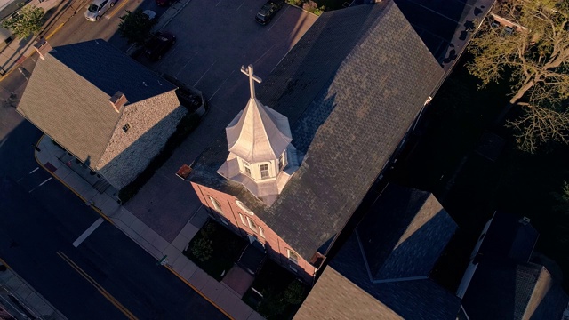 日落时分，鸽子飞过宾夕法尼亚州小镇巴斯的教堂上空。阿巴拉契亚山脉，美国宾夕法尼亚州。无人机用静态摄像头拍摄视频，上升运动。视频素材