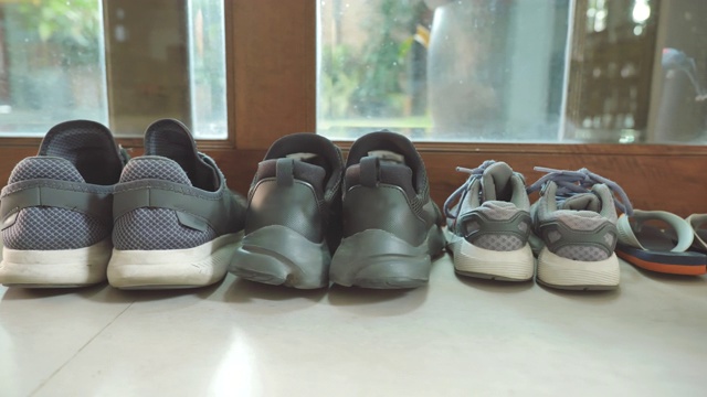 在家里门前，父亲的鞋和母亲的鞋紧挨着儿子的鞋的场景，家庭物品的概念视频下载