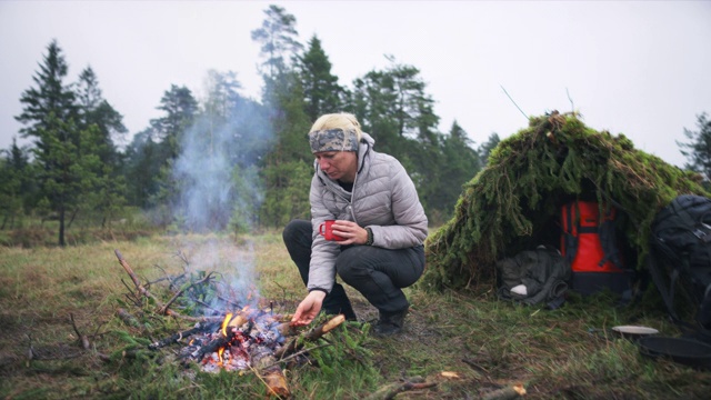 DS女性野外生存专家在大自然的火边做饭视频下载