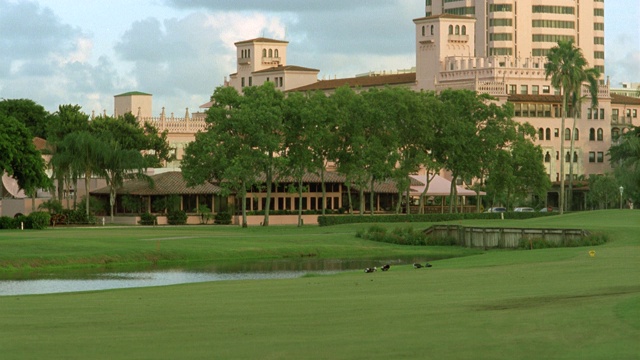 大厦前广角高尔夫球场，高档酒店。看到赛道上的沙坑和背景中的棕榈树。视频下载