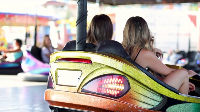 两个年轻女人在游乐场玩碰碰车。视频素材