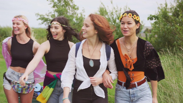 一群年轻的女性朋友带着露营装备穿过田野去音乐节-用慢镜头拍摄视频下载