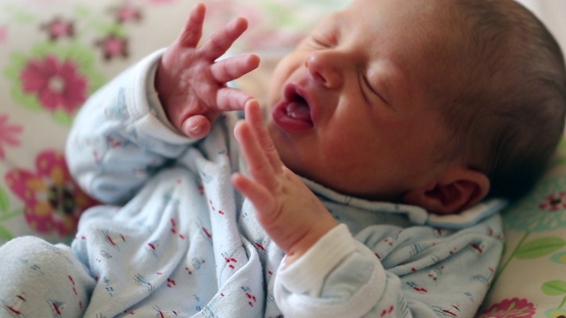 刚出生一周的小婴儿睡觉时做鬼脸，做鬼脸伸展身体视频素材