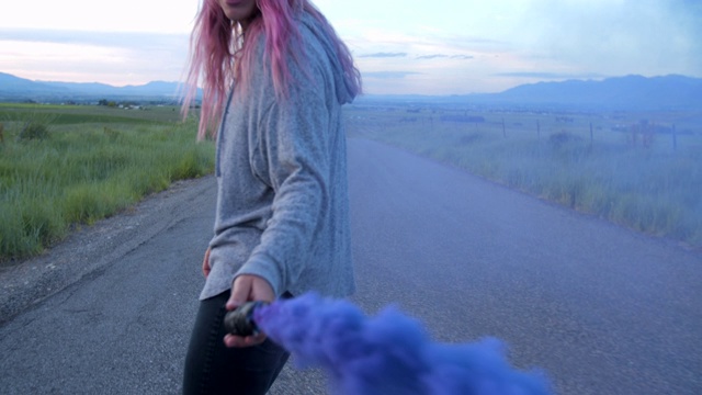 一个粉色头发的少女在玩滑板的时候玩弄着蓝色的烟雾视频素材