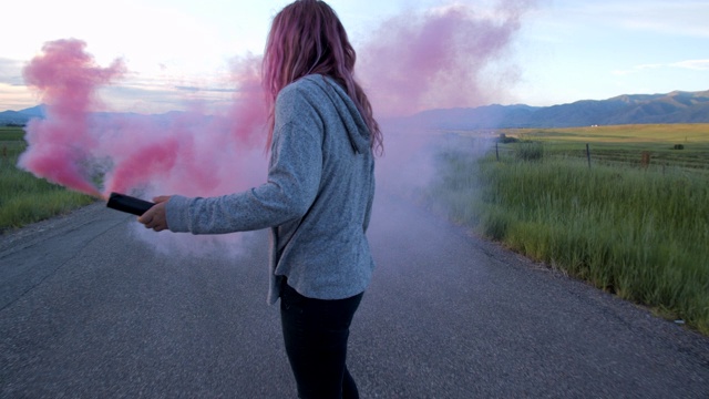 少女与粉红色的头发玩粉红色的烟雾，而滑板视频素材
