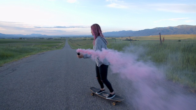 一个粉色头发的少女在一条路上玩滑板视频素材
