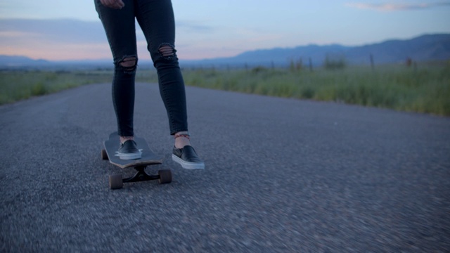 一个粉色头发的少女在一条路上玩滑板视频素材