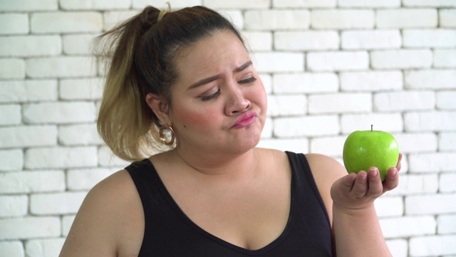 特写正面视图:泰国超重妇女是无聊吃青苹果或健康食品视频下载