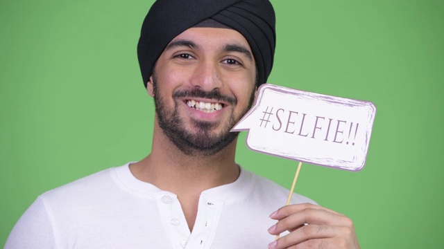 快乐的年轻英俊的胡子印度男人的脸与自拍纸标志视频下载