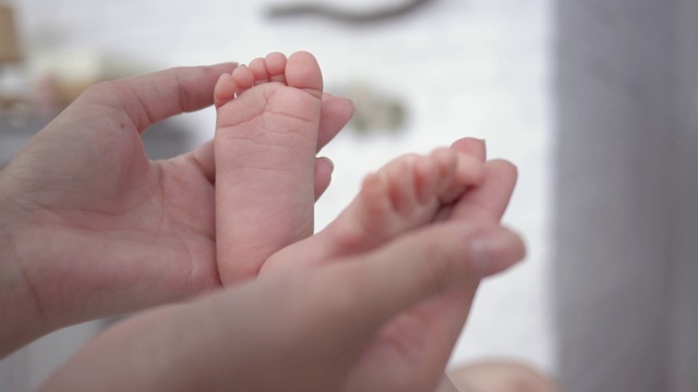 母性，母亲关怀的双手抚摸着小新生儿的脚视频素材