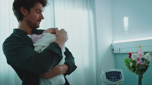 快乐的父亲抱着熟睡的新生儿在病房里视频下载