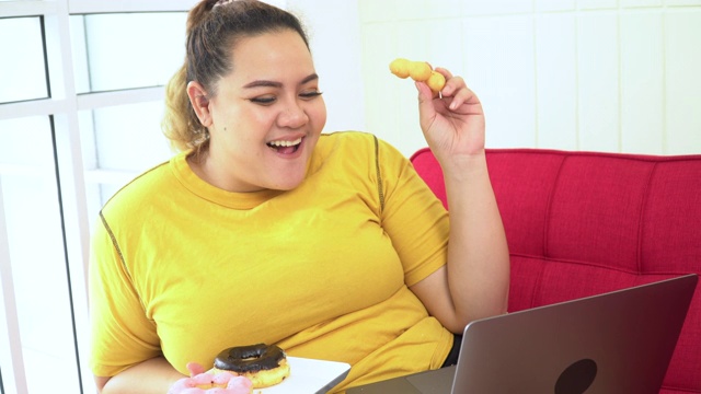 身材高大的女人在家里吃零食和看电脑视频素材
