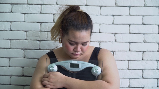 体型大的亚洲女人悲伤与体重秤视频素材