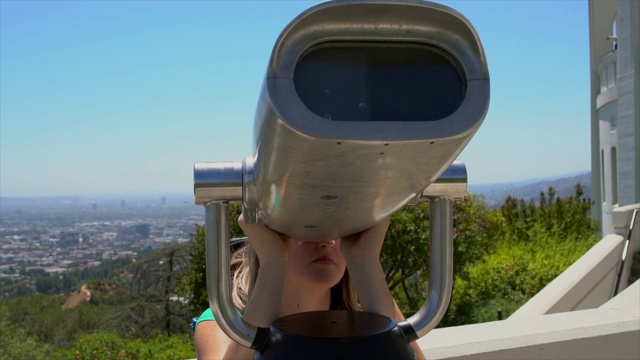 慢镜头白人妇女通过双筒望远镜看城市天际线视频下载