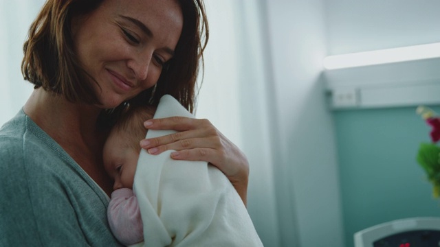 体贴的年轻母亲微笑着拥抱着婴儿视频下载