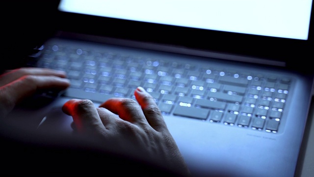电脑黑客在他的笔记本电脑上输入代码，特写视频下载