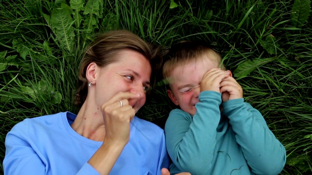 母亲和儿子躺在草地上，玩耍，笑着视频素材