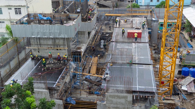 繁忙的工业建筑工地工人用起重机工作的鸟瞰图。中午发展高层建筑大楼俯视图。视频下载