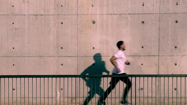 全长视野的男性运动员在白色t恤跑对着城市混凝土墙与空白的广告复制空间区域视频下载