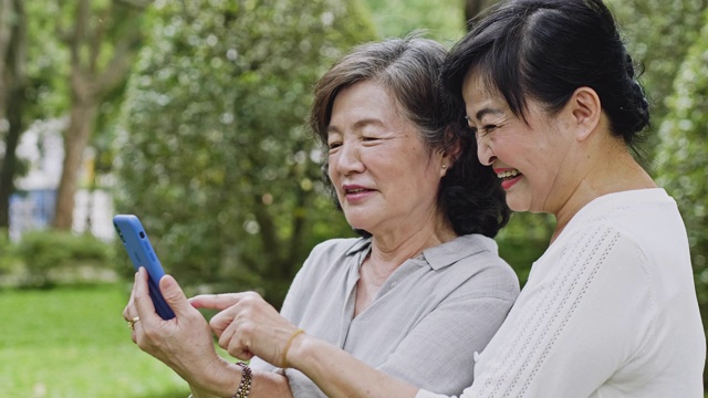 两位台湾资深女性一边看智能手机一边笑视频素材