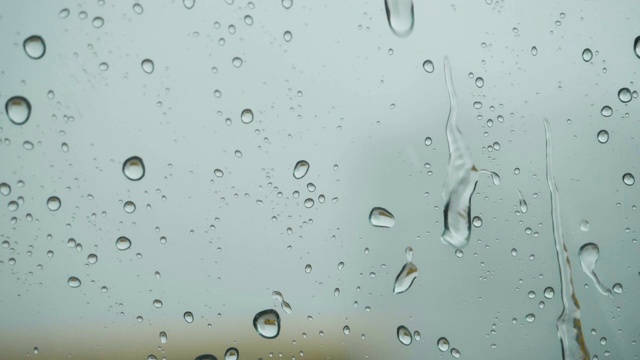 雨点落在窗外的玻璃上。关闭了。缓慢的运动。雨落在玻璃上。雨滴落在车窗背景上。秋天天气不好。视频素材