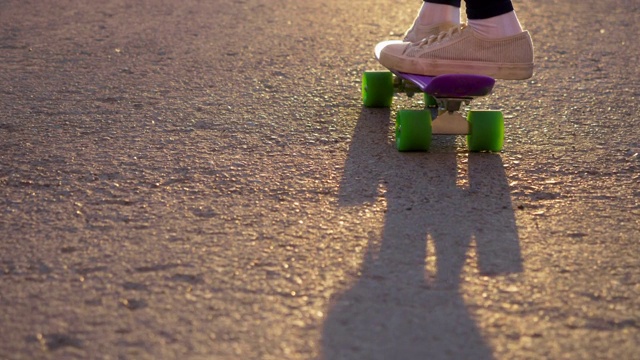 穿着白色运动鞋踩着滑板的女孩在柏油路上推着自己，斯洛莫。视频素材