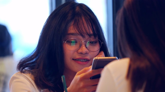 两个亚洲女性朋友在咖啡馆里使用手机视频素材