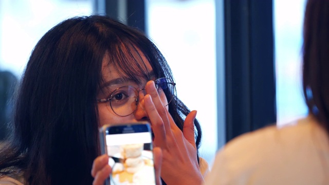 两个亚洲女性朋友在咖啡馆里使用手机视频素材
