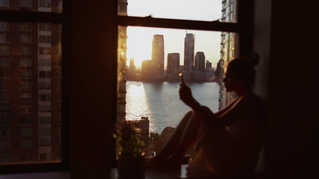 在纽约，一个拿着手机的女人站在窗边视频素材