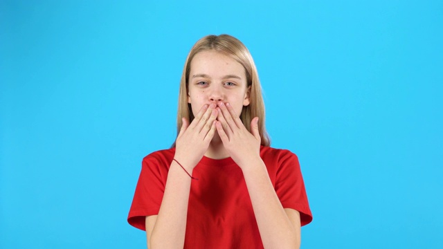 小女孩摆姿势和飞吻在蓝色的背景视频下载