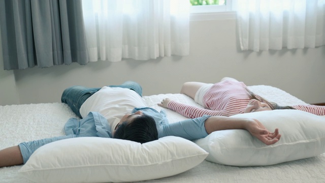 幸福的家庭，爸爸和女儿小女孩躺在卧室的白色床上玩耍视频下载